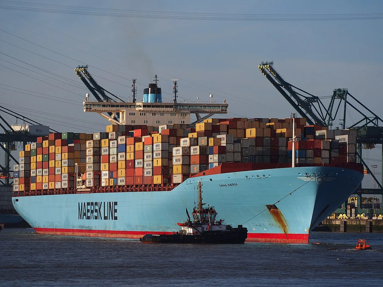 Emma Maersk on the Scheldt near Antwerp, with tugs and container cranes..